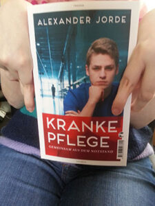 Hände halten das Buch "Kranke Pflege"